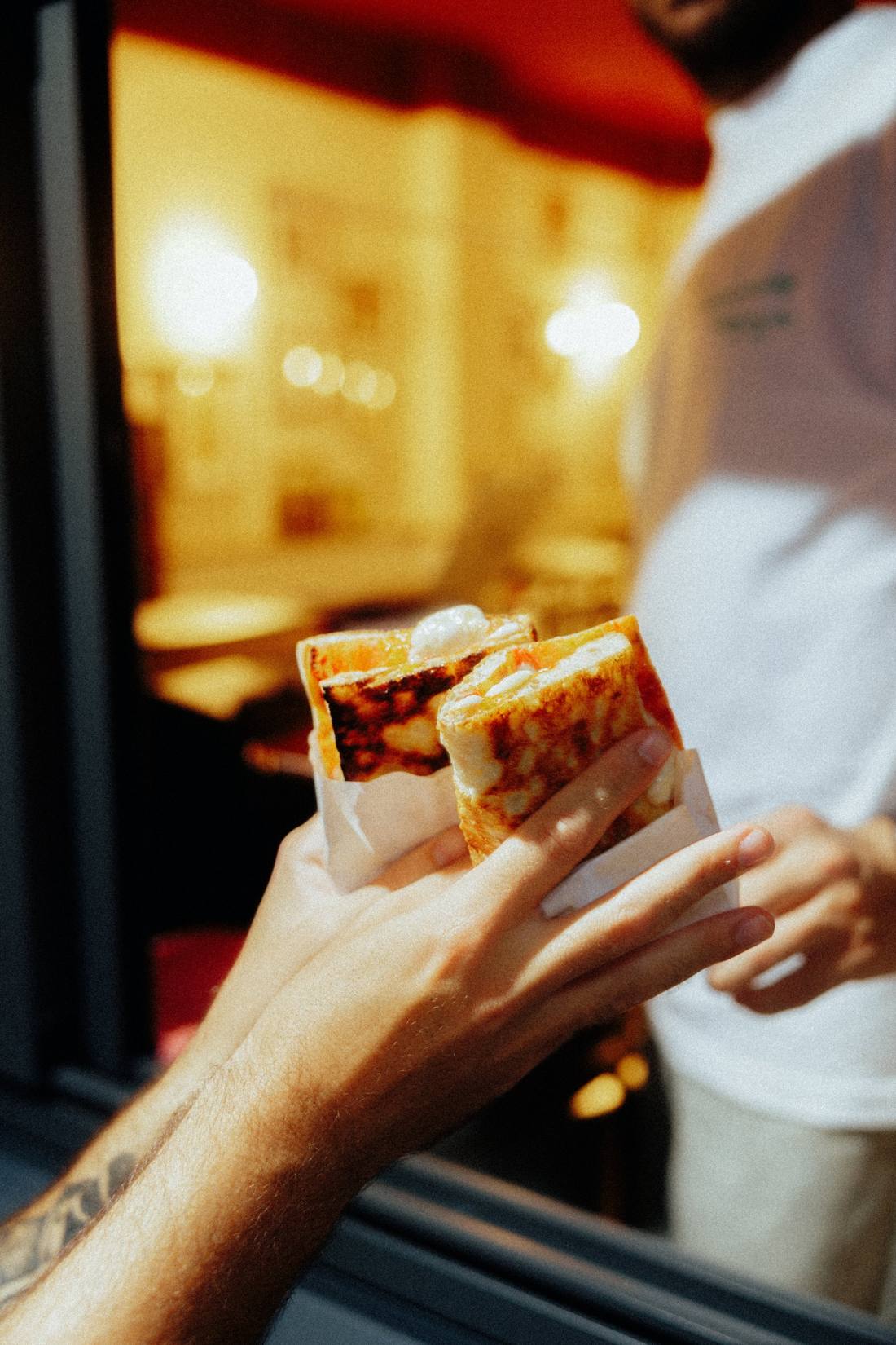 Due pizzette al taglio piegate nella carta, passate dalla finestrella